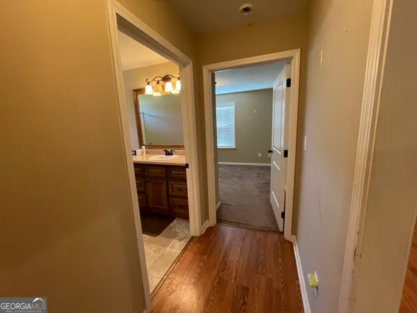 a view of a hallway with wooden floor and a bathroom