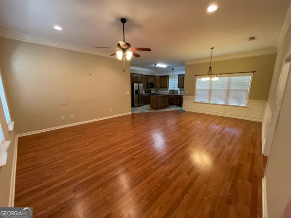 an empty room with wooden floor ceiling fan and windows