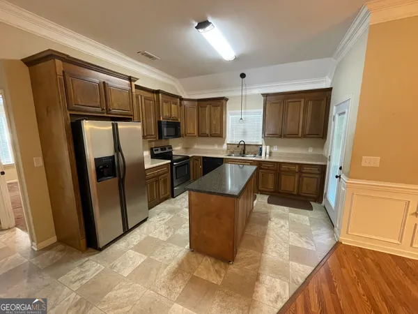 a kitchen with stainless steel appliances granite countertop a refrigerator a sink a stove a microwave and island