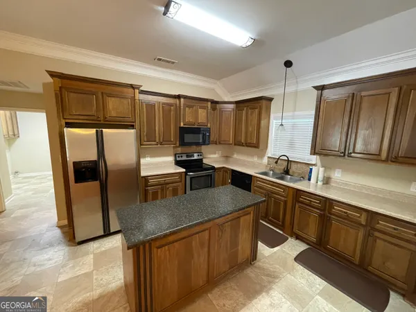 a kitchen with stainless steel appliances granite countertop a sink stove refrigerator and cabinets