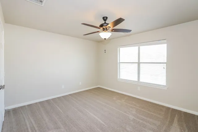 an empty room with a window and a fan