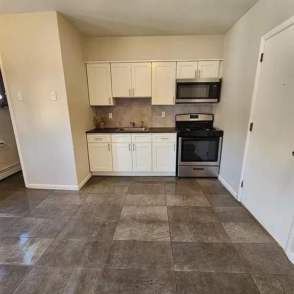 14 Cooper Street, Unit 2F Bayonne, NJ 07002 - Photo 2 of 6 a kitchen with stainless steel appliances a stove a microwave and a refrigerator