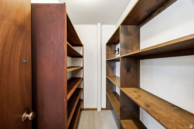 299 West Center Street, Unit 2 Logan, UT 84321 - Photo 16 of 46 Dedicated storage room featuring extensive built-in wooden shelving, a solid wood-paneled door with a brass knob, light wood-finish flooring, and crisp white walls