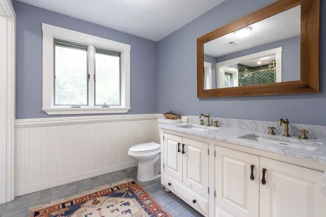 a bathroom with a granite countertop toilet sink and mirror