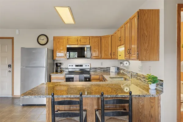 a kitchen with kitchen island granite countertop a sink cabinets and stainless steel appliances