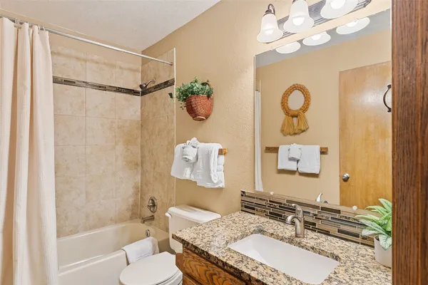 a bathroom with a granite countertop sink a mirror and a bathtub