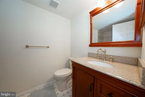 a bathroom with a granite countertop sink a toilet and a mirror