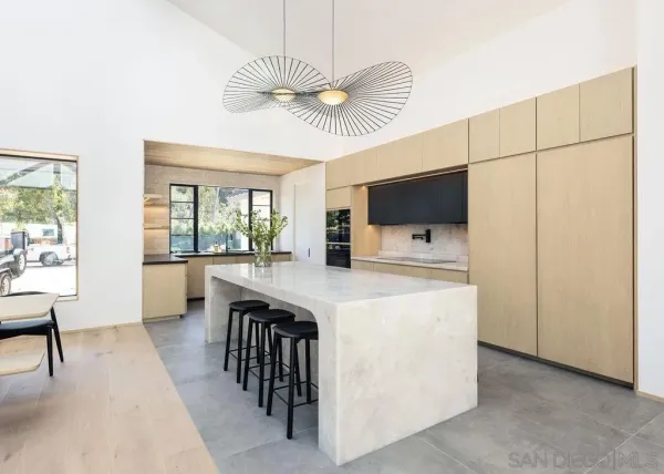 a kitchen with kitchen island a stove a sink a dining table and chairs with wooden floor