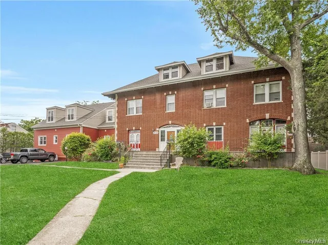 a front view of a house with a yard and trees