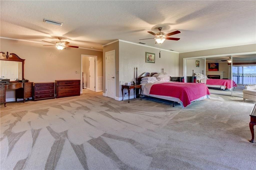 910 North Kepler Road DeLand, FL 32724 - Photo 22 of 52 a bedroom with a large bed and a chandelier