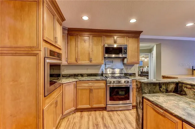 a kitchen with stainless steel appliances kitchen island granite countertop a dining table chairs and wooden floor