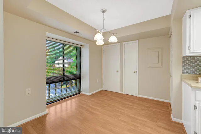 a view of an empty room with window and wooden floor
