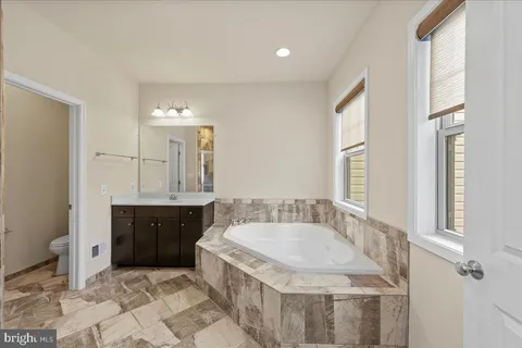 a spacious bathroom with a granite countertop tub sink and mirror