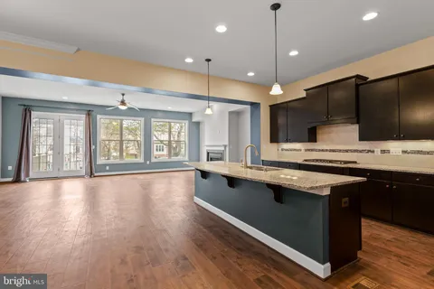a kitchen with stainless steel appliances granite countertop a sink a stove and a wooden floors