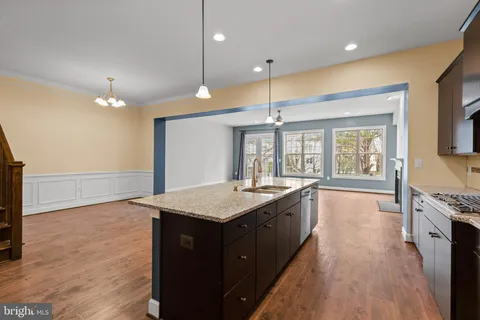 a kitchen with granite countertop a stove a sink a center island and wooden floor