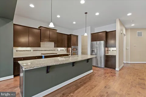 a large kitchen with a large counter top a refrigerator and stainless steel appliances
