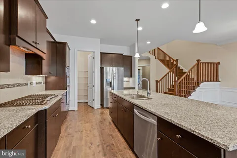 a kitchen with kitchen island granite countertop a sink a counter space appliances and cabinets
