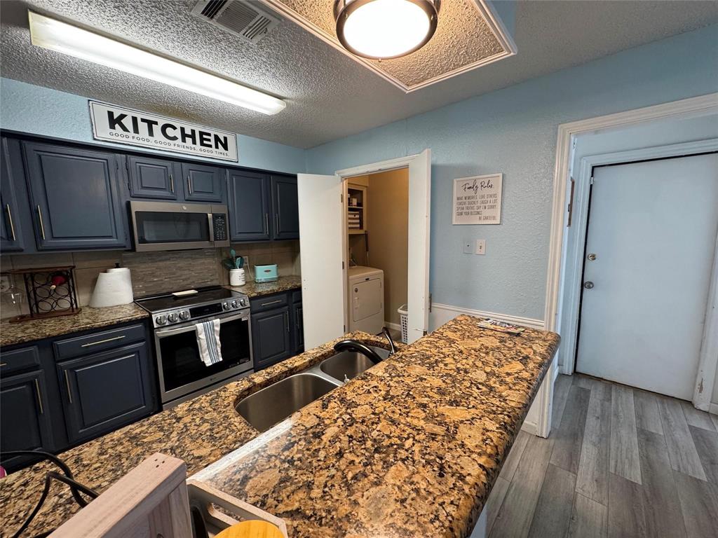 2412 Ridgestone Drive Dallas, TX 75287 - Photo 15 of 23 a kitchen with stainless steel appliances kitchen island granite countertop a stove refrigerator and microwave