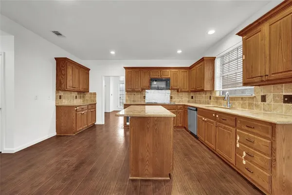 a kitchen with wooden floors and wooden cabinets