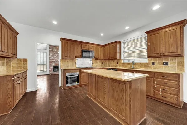 a kitchen with stainless steel appliances granite countertop wooden cabinets a sink dishwasher a stove and a refrigerator