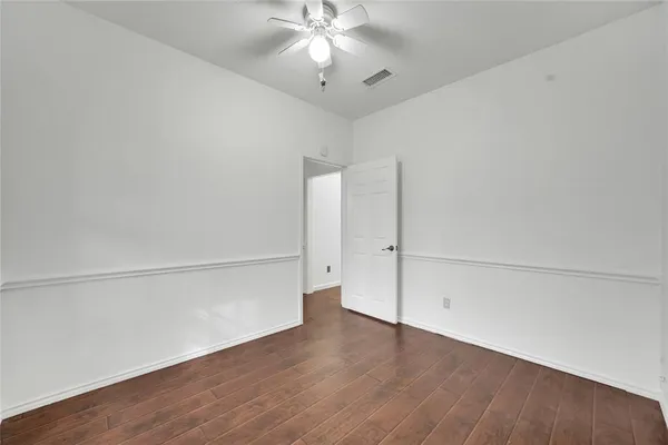 an empty room with wooden floor and fan