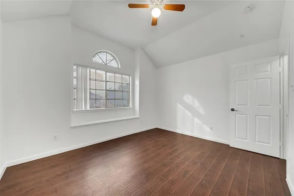 an empty room with wooden floor cabinet and windows