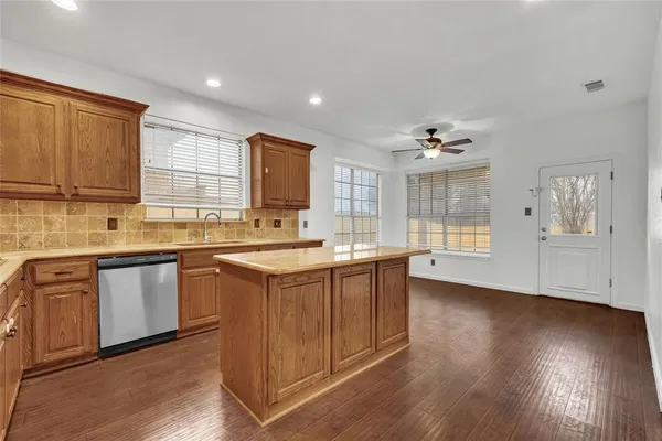 a kitchen with stainless steel appliances granite countertop a sink dishwasher stove and wooden cabinets with wooden floor