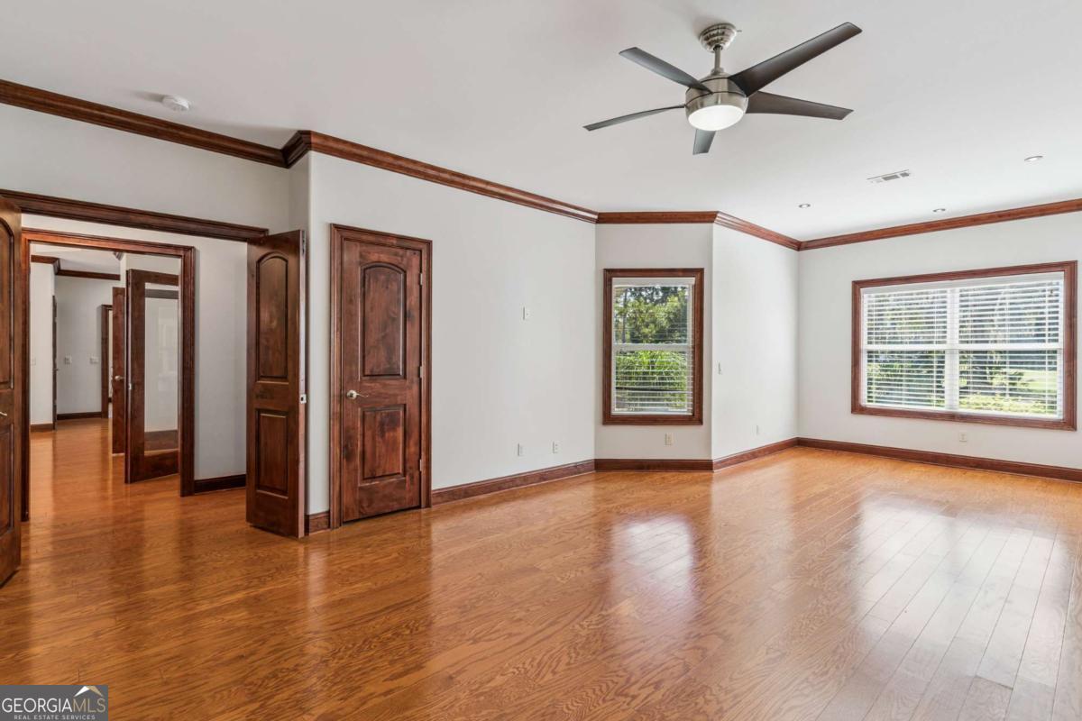 150 Rice Mill St. Simons Island, GA 31522 - Photo 14 of 38 an empty room with wooden floor chandelier fan and windows