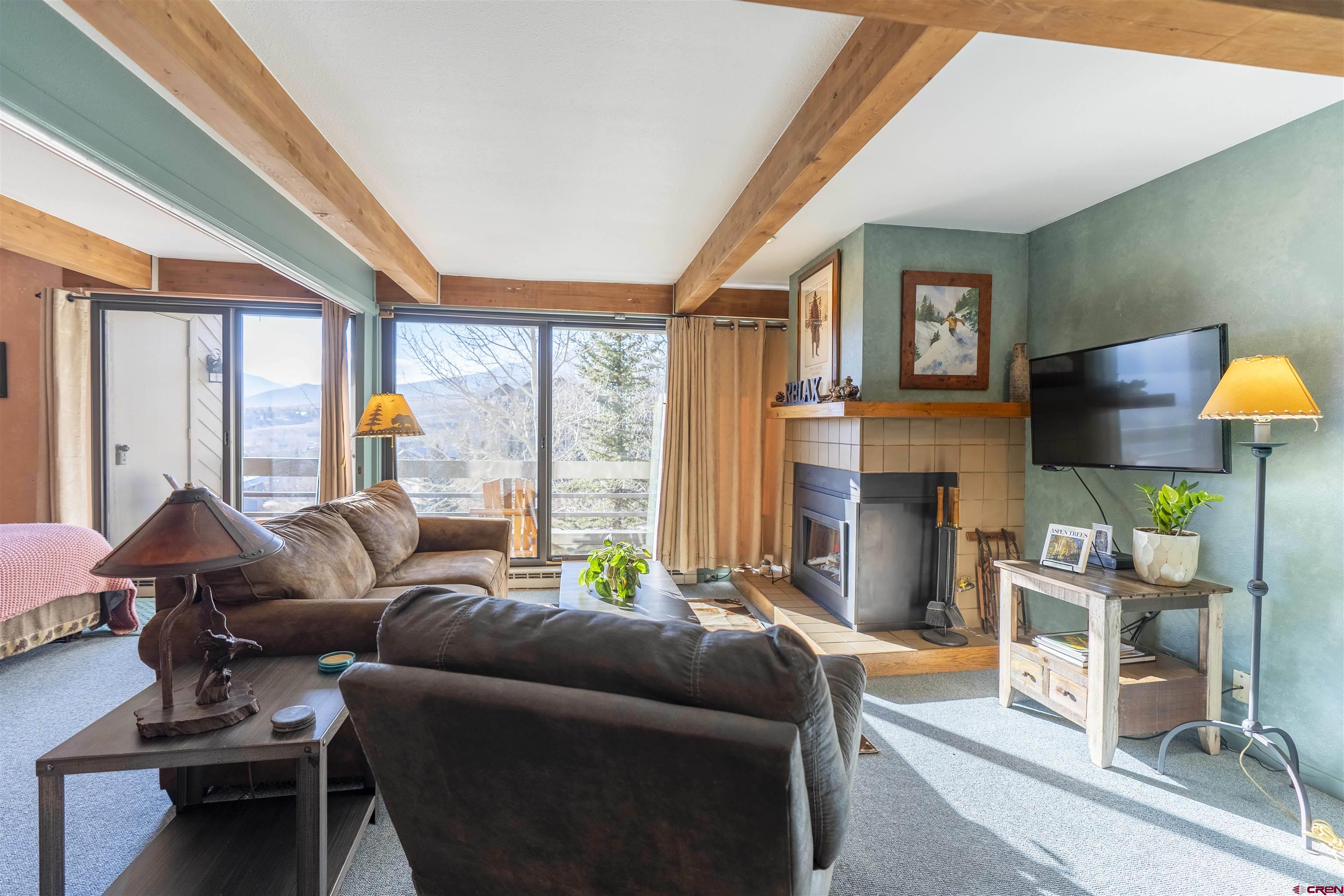 11 Hunter Hill Road, Unit 406 Crested Butte, CO 81225 - Photo 13 of 45 a living room with furniture a fireplace and a large window