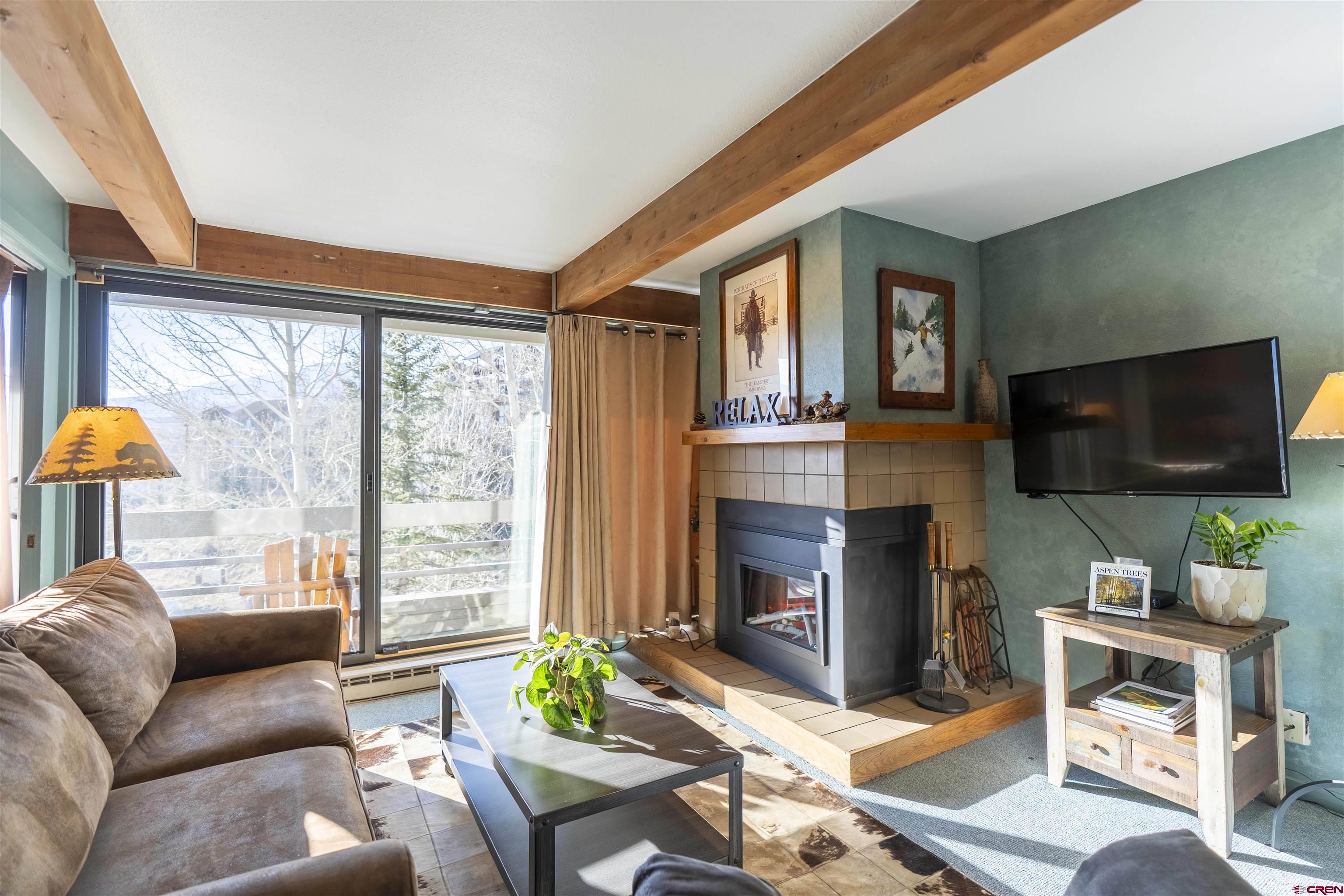 11 Hunter Hill Road, Unit 406 Crested Butte, CO 81225 - Photo 14 of 45 a living room with furniture a flat screen tv and a fireplace