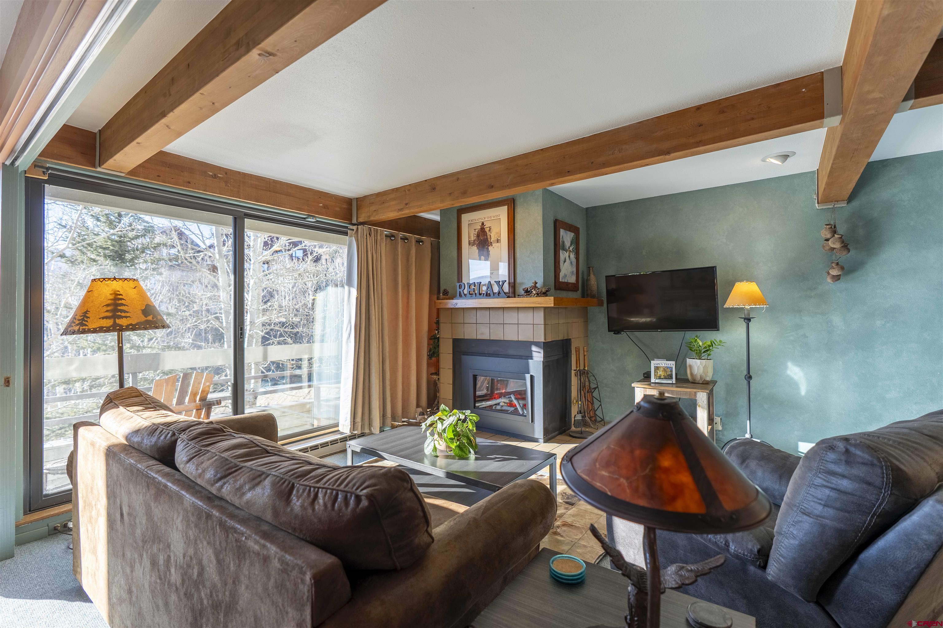 11 Hunter Hill Road, Unit 406 Crested Butte, CO 81225 - Photo 15 of 45 a living room with fireplace furniture and a floor to ceiling window