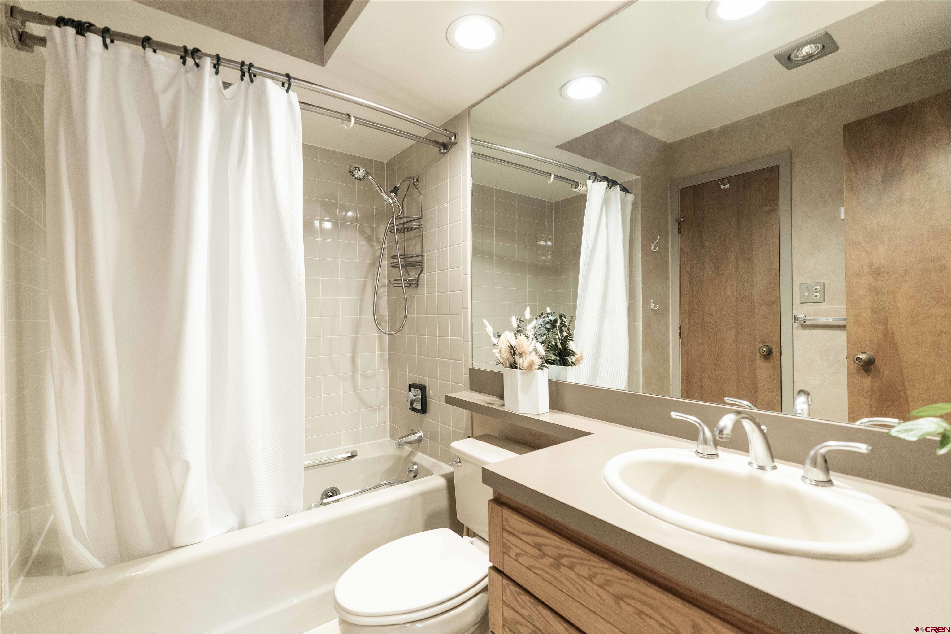 11 Hunter Hill Road, Unit 406 Crested Butte, CO 81225 - Photo 23 of 45 a bathroom with a sink toilet a mirror and shower