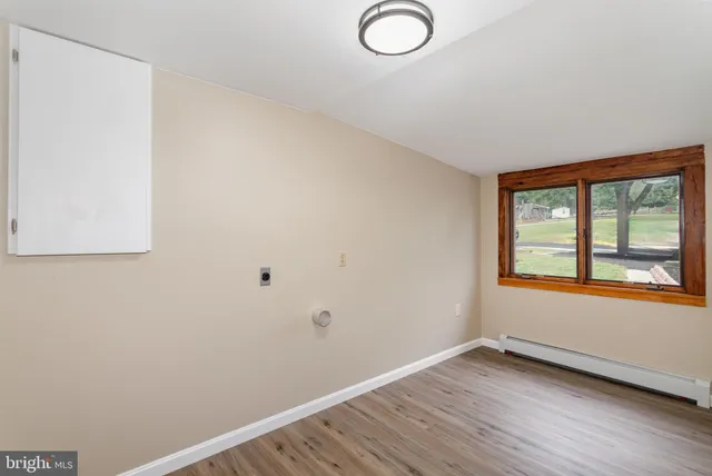 an empty room with wooden floor and window