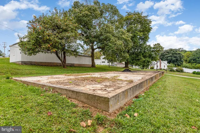 a view of a white house next to a yard and road