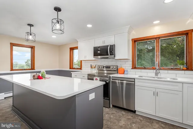 a large kitchen with kitchen island a sink stainless steel appliances and cabinets