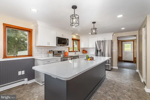 a open kitchen with kitchen island white cabinets and stainless steel appliances