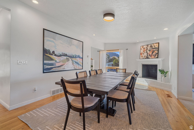 4426 South 3035 East Holladay, UT 84124 - Photo 10 of 49 Dining area with a tile fireplace, a textured ceiling, light wood-style flooring, and recessed lighting