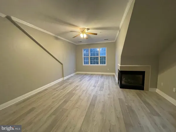 an empty room with wooden floor fireplace and windows