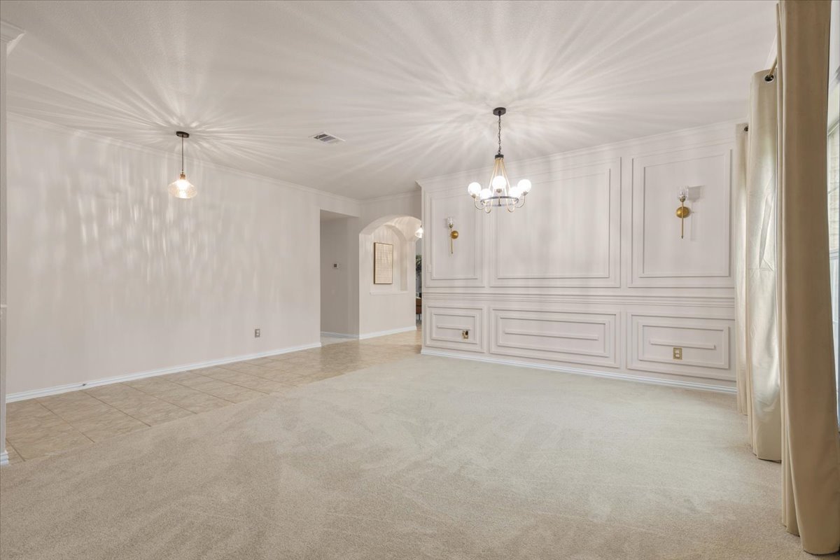 2501 Aspen Meadow Road Leander, TX 78641 - Photo 17 of 30 Spacious interior featuring a decorative accent wall with panel molding and integrated sconces, plush carpet flooring, a multi-bulb chandelier, and a recessed ceiling light