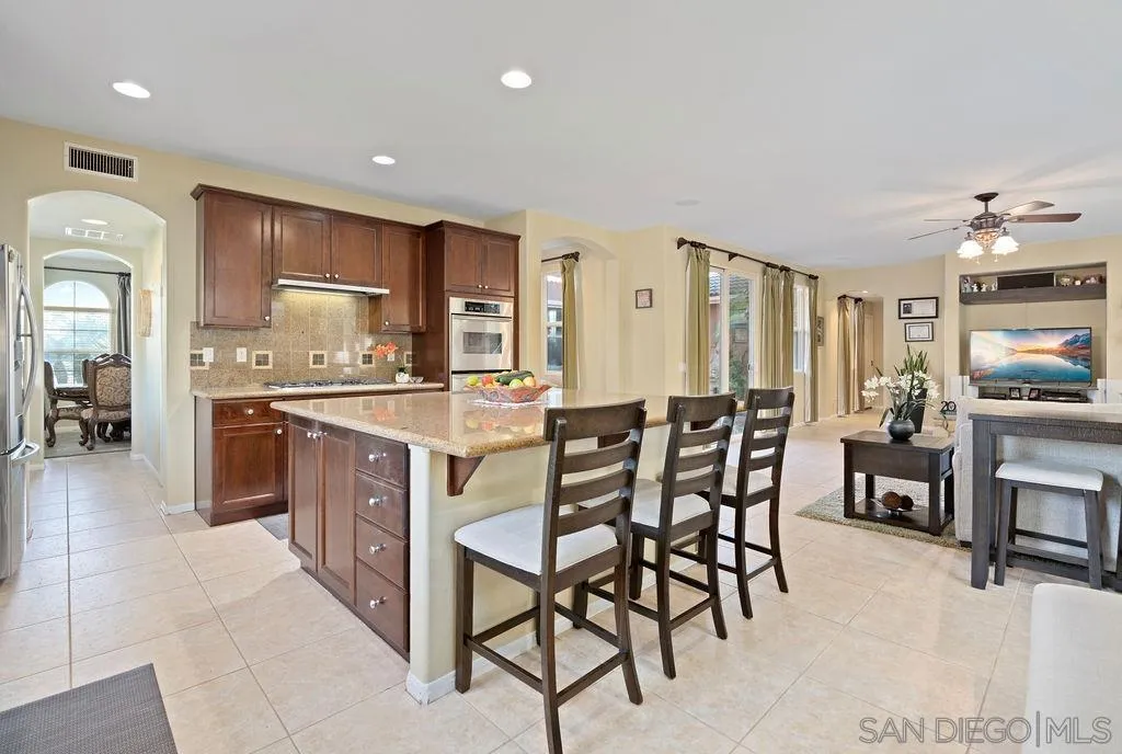 197 Double Eagle Glen Escondido, CA 92026 - Photo 11 of 70 a kitchen with stainless steel appliances kitchen island granite countertop a table and chairs in it