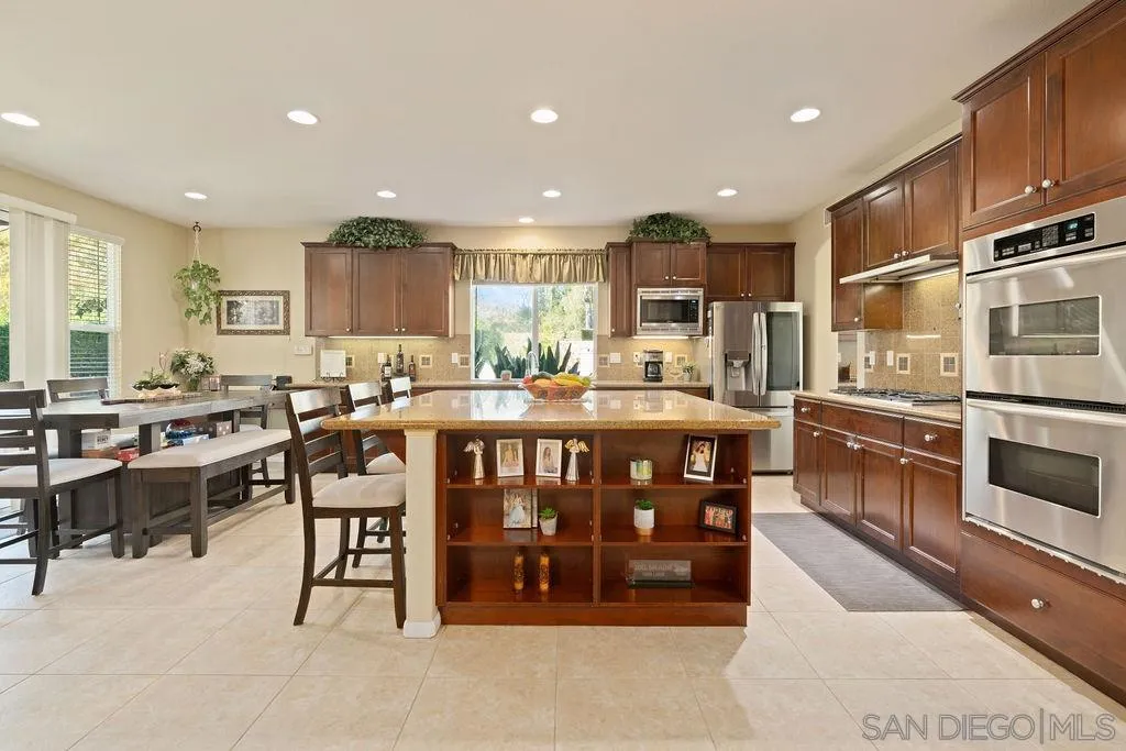 197 Double Eagle Glen Escondido, CA 92026 - Photo 12 of 70 a kitchen with stainless steel appliances kitchen island granite countertop a stove a sink a dining table and chairs