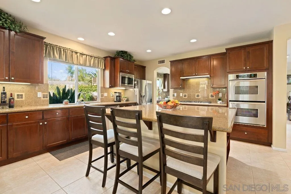 197 Double Eagle Glen Escondido, CA 92026 - Photo 13 of 70 a kitchen with a table chairs refrigerator and cabinets