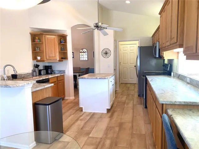 a large kitchen with stainless steel appliances granite countertop a sink and wooden cabinets