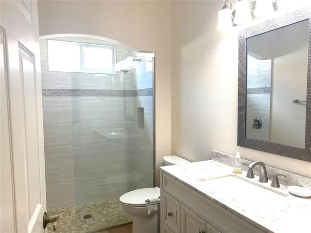 a bathroom with a granite countertop sink toilet a mirror and shower