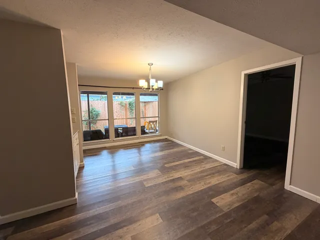 an empty room with wooden floor fireplace and windows