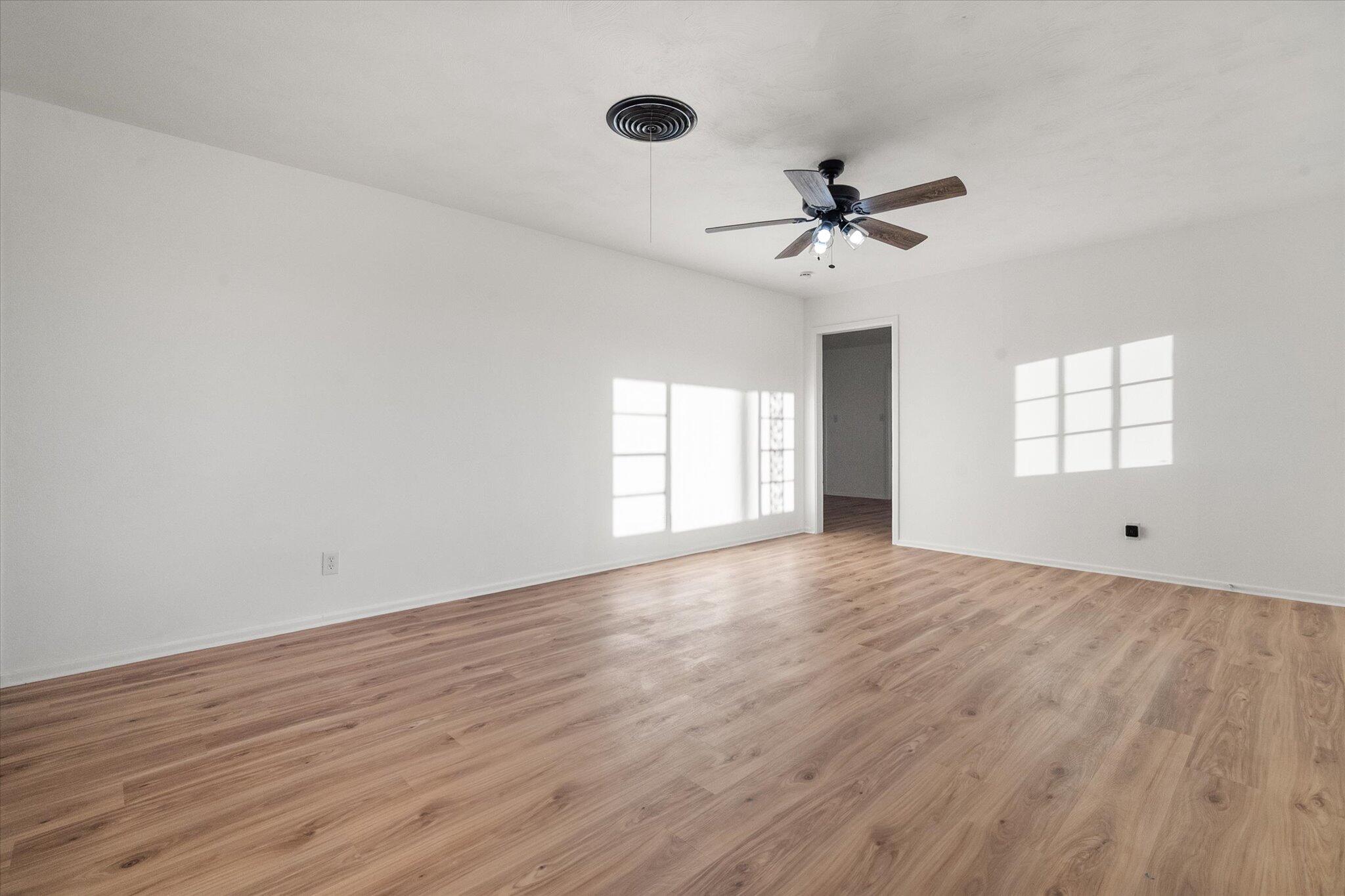 1312 Culpepper Avenue Wilson, TX 79381 - Photo 11 of 27 an empty room with wooden floor ceiling fan and windows