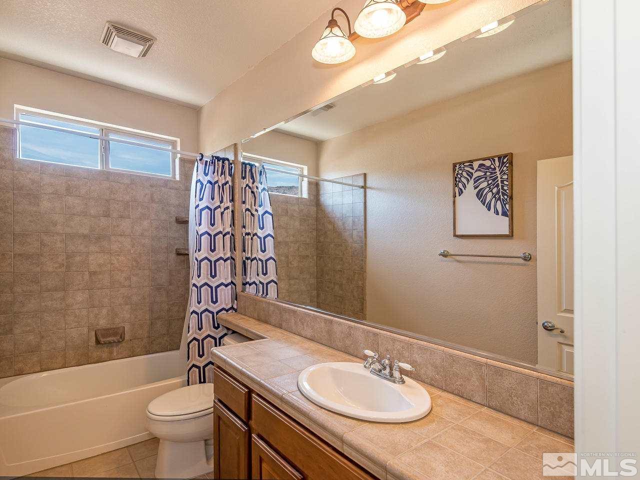 2598 Spring Flower Drive Reno, NV 89521 - Photo 18 of 21 a bathroom with a granite countertop sink toilet a mirror and shower