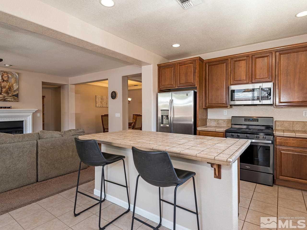 2598 Spring Flower Drive Reno, NV 89521 - Photo 10 of 21 a kitchen with stainless steel appliances granite countertop a stove top oven a sink a refrigerator and white cabinets