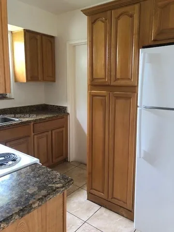 a kitchen with granite countertop cabinets and refrigerator