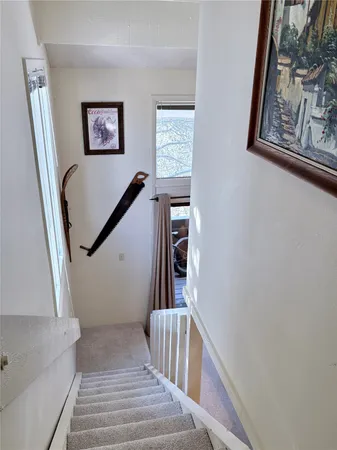 a view of staircase with lots of frames on wall and a window